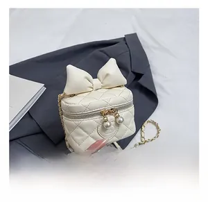 Detail of cream quilted mini bag with cute cat embroidery, bow, and pearl zippers