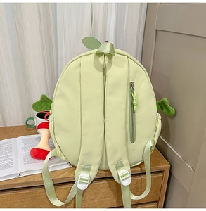 Detail of light green cartoon backpack featuring leaf top handle and anti-theft back pocket