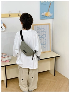 Vista posteriore di un bambino con borsa a tracolla in nylon verde oliva e tracolla nera