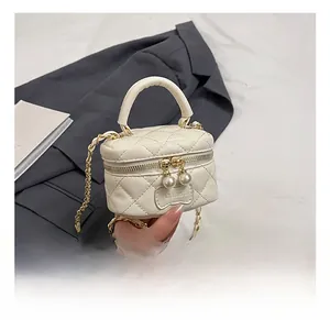 Close-up of quilted cream mini bag featuring double pearl zipper and gold chain strap