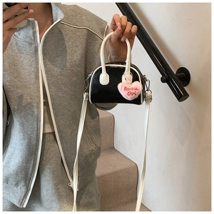Detailed view of mini patent leather shell bag with pink heart plush Barbie charm