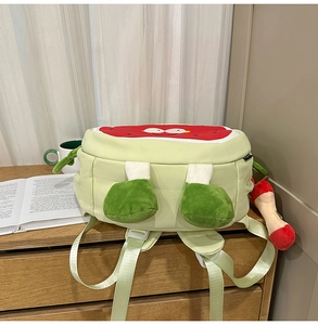 Close-up of a light green watermelon themed backpack with plush feet and fruit pendant