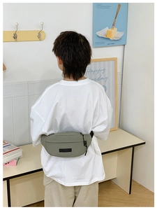 Vista posteriore di un bambino con marsupio in nylon grigio-verde in un interno sobrio