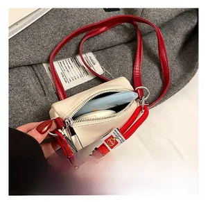Dettaglio dell'interno della mini borsa crema con tracolla rossa e spazio per i cosmetici