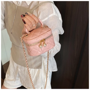 Gros plan du sac bandoulière rose matelassé avec breloques perles et chaîne en métal