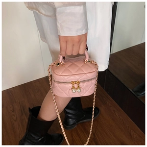Detail view of pink quilted mini bag with pearl zipper pull and gold chain strap