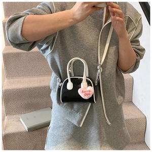 Detail of mini black and white shell bag with pink Barbie Girl plush heart charm