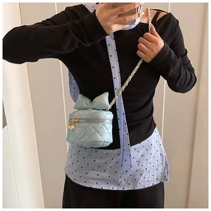 Detail of light blue quilted mini crossbody bag with bow decoration and pearl charms