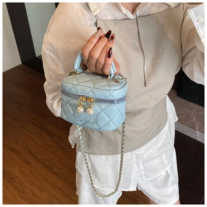 Détail du mini sac matelassé bleu clair avec fermeture perle et chaîne dorée