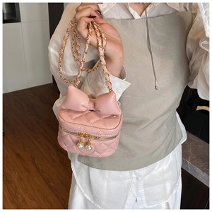 Detail of pink quilted crossbody bag for kids with bow decoration and pearl zipper
