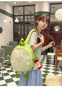 Detail of cute green fruit-shaped backpack with 3D limbs and decorative charm
