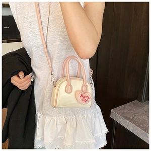 Close-up of a mini shell bag with Barbie Girl embroidery and a plush heart charm