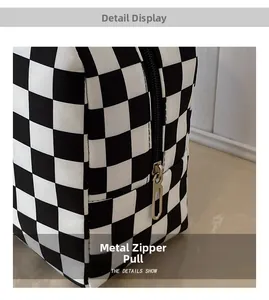 Detail show of silver metal zipper puller on black and white checkered lunch bag