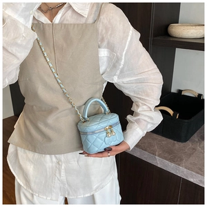 Gros plan du mini sac boîte matelassé bleu clair avec chaîne dorée et perles