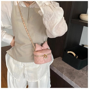 Close-up of pink quilted crossbody bag with oversized bow and pearl zipper detail