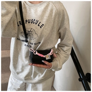 Dettaglio della mini borsa a cuscino nera con corda rosa annodata e ciondolo a sfera
