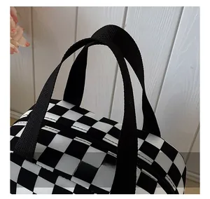 Detail of the durable black nylon handle with reinforced stitching on checkered lunch bag
