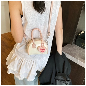 Detailed view of mini shell bag with pink patent handles and Barbie Girl heart pendant