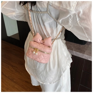 Detail of pink quilted crossbody bag for girls with bow, pearl charm and chain strap