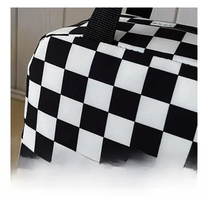 Detailed macro view of checkerboard fabric and black woven handle on this lunch bag