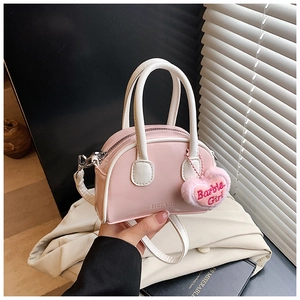 Detailed close-up of pink shell handbag with heart plush charm and adjustable strap