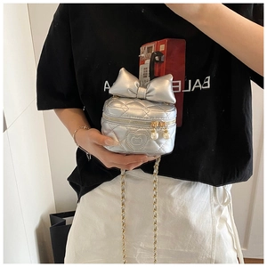 Silver quilted mini bag with a large bow detail and pearl zipper charm closeup