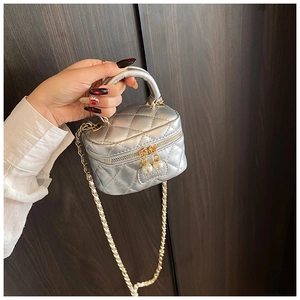 Détail d'un mini sac argenté matelassé avec zip perlé et bandoulière en chaîne