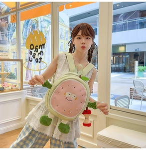 Detail view of cute cartoon fruit backpack with plush decorations and soft green straps