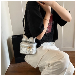 Close-up of silver quilted crossbody bag with bow, cat patch, and pearl zipper detail