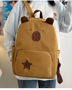 Détail d'un sac à dos capybara jaune avec oreilles d'ours et écusson étoile