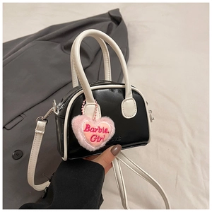 Detail view of mini black shell bag with white handle and pink Barbie Girl heart pendant