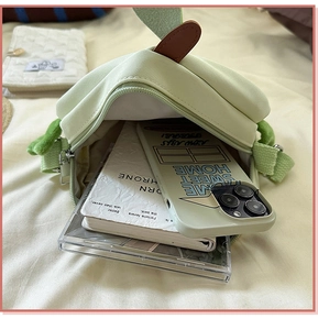 Detail showing inner storage of green fabric crossbody bag with phone and notepad inside