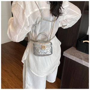 Détail du mini sac boîte argenté matelassé avec chaîne dorée porté par un enfant