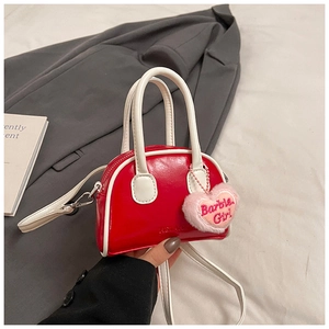 Close-up of red patent leather mini handbag with a pink Barbie plush heart pendant charm