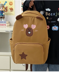 Détail d'un sac à dos jaune avec broderie ours et écusson étoile sur la poche avant