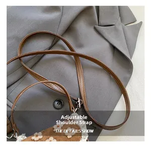 Détail de la bandoulière marron réglable avec accents de dentelle florale sur sac blanc