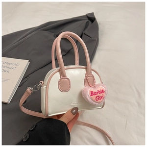 Close-up of mini white shell handbag with pink handles and plush heart charm