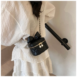 Quilted mini crossbody box bag with oversized bow and pearl charms worn by model