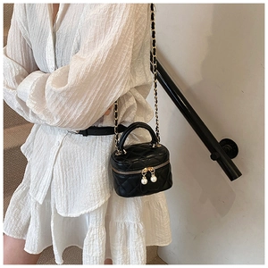 Detail of mini black quilted bag featuring pearl double zippers and chain strap