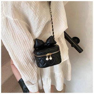 Close-up of black quilted heart crossbody bag with bow and pearl zipper detail