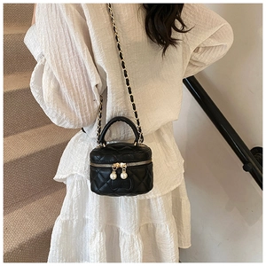 Détails du mini sac noir matelassé avec d'élégants zips en perles et une bandoulière dorée