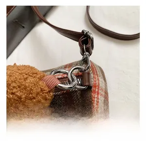 Detail of silver metal swivel hook and brown leather strap on plush checkered bag