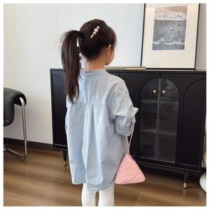 Detail der rosa gesteppten Dreieckstasche und des blauen Langarmshirts für Mädchen
