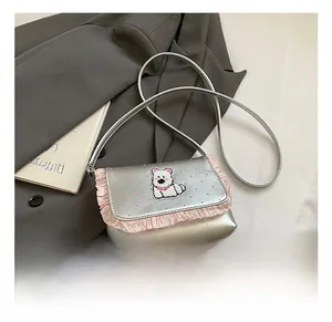 Close-up of silver polka dot crossbody bag with pink ruffles and dog patch