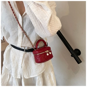 Detail of red quilted mini bag featuring elegant pearl charms and woven chain strap