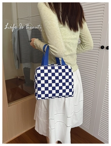 Detail showing the blue and white checkered lunch bag carried by a person in a lifestyle setting