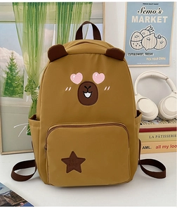 Détail du sac à dos capybara jaune avec écusson en étoile et oreilles brunes