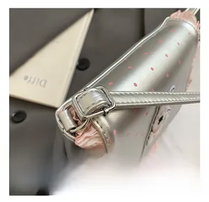 Detail of adjustable silver shoulder strap with pink polka dot pattern and ruffled trim