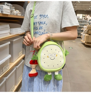 Detail of cute green fruit crossbody bag with embroidered face and red apple charm