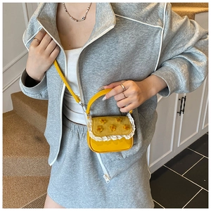 Détail du mini sac bandoulière jaune avec fleurs 3D et bordure en dentelle blanche